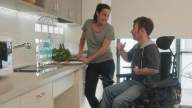 A care worker discusses meals with a person using a wheelchair in the kitchen.