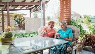 A shot of two senior friends laughing and enjoying a cup of tea together outside.