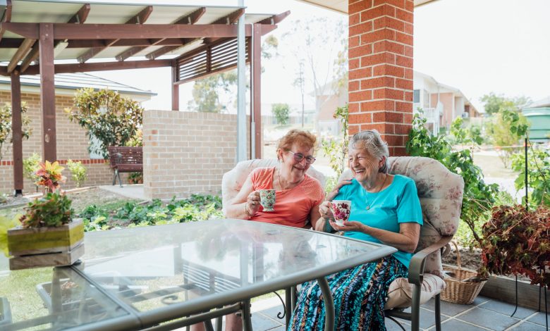 A shot of two senior friends laughing and enjoying a cup of tea together outside.