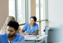Working together at the library, the young adult female nursing student listens to her unrecognizable female friend.