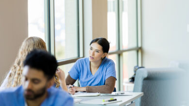 Working together at the library, the young adult female nursing student listens to her unrecognizable female friend.