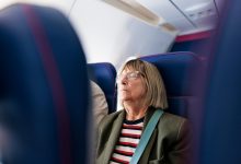 Senior woman travelling by plane. She is sleeping.