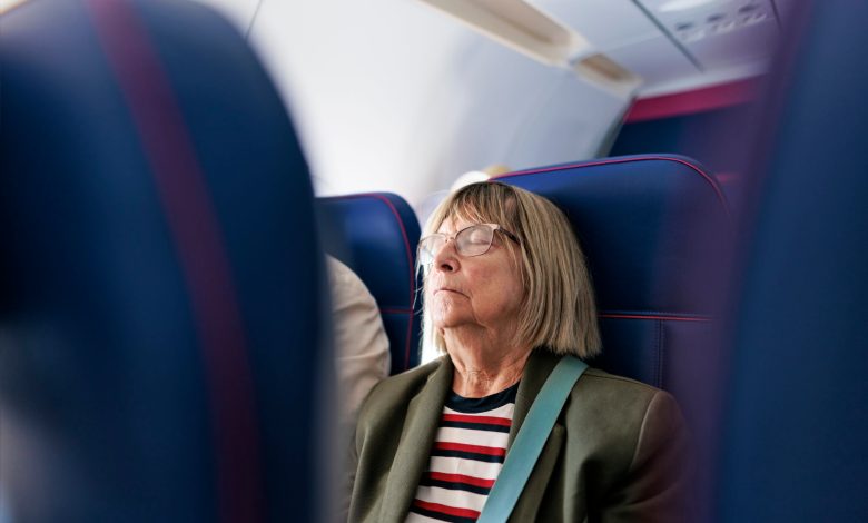 Senior woman travelling by plane. She is sleeping.
