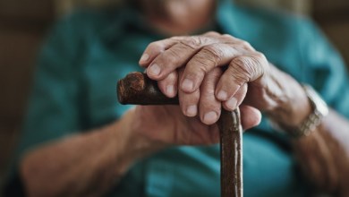 Cropped shot of an unrecognizable man leaning on his walking stick