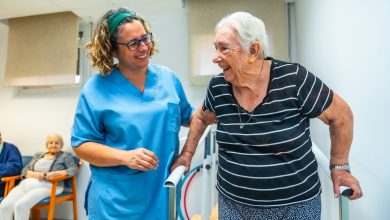 Senior patient doing physiotherapy at a geriatrics with help of a therapist walking on parallel bars