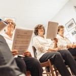 Senior Women Holding Music Sheets at Choir Practice.