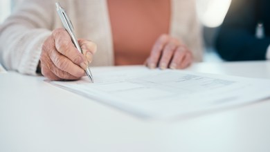 Senior hand signing finance paperwork, will agreement and pension fund contract while planning budget, banking and investing. Closeup of old, aged and retired woman calculating expenses and spending