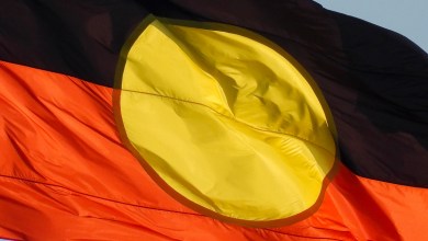 The Australian Aboriginal flag flies on the Sydney Harbour Bridge. This image was taken from the foreshore of Sydney Harbour at Kirribilli on a sunny afternoon before sunset on 13 April 2024.