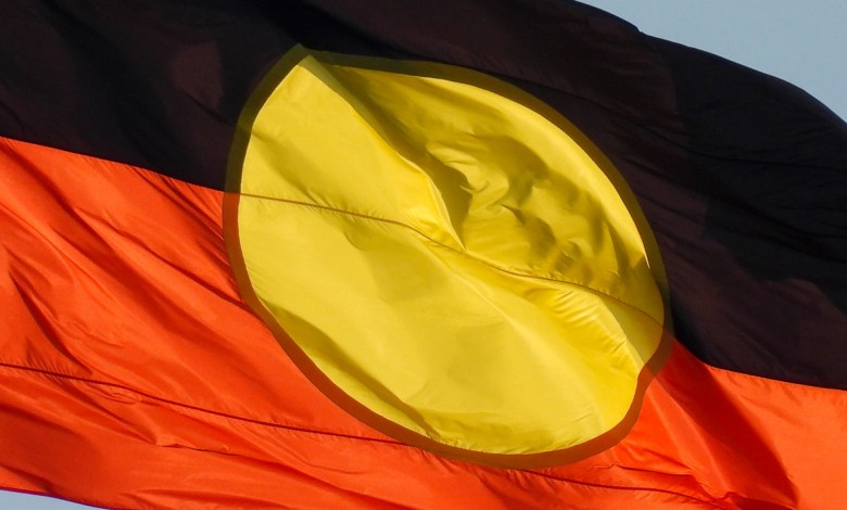 The Australian Aboriginal flag flies on the Sydney Harbour Bridge. This image was taken from the foreshore of Sydney Harbour at Kirribilli on a sunny afternoon before sunset on 13 April 2024.