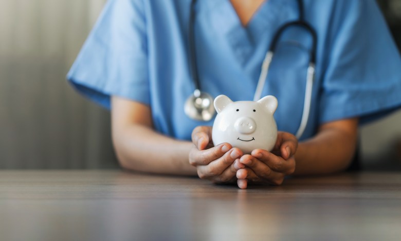 Nurse or doctor with stethoscope holding piggy bank in hand. Concept of medical expenses, finance, saving money, health insurance, medicine, donation and pension. Healthcare service cost.