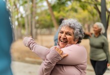 Senior woman stretching and talking friend at public park