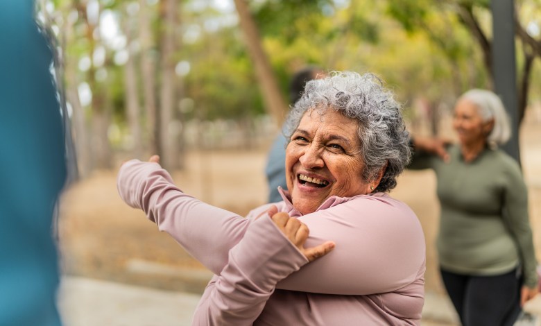 Senior woman stretching and talking friend at public park