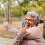 Senior woman stretching and talking friend at public park