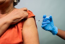 Close-up of a doctor's hand vaccinating a woman in a studio shot