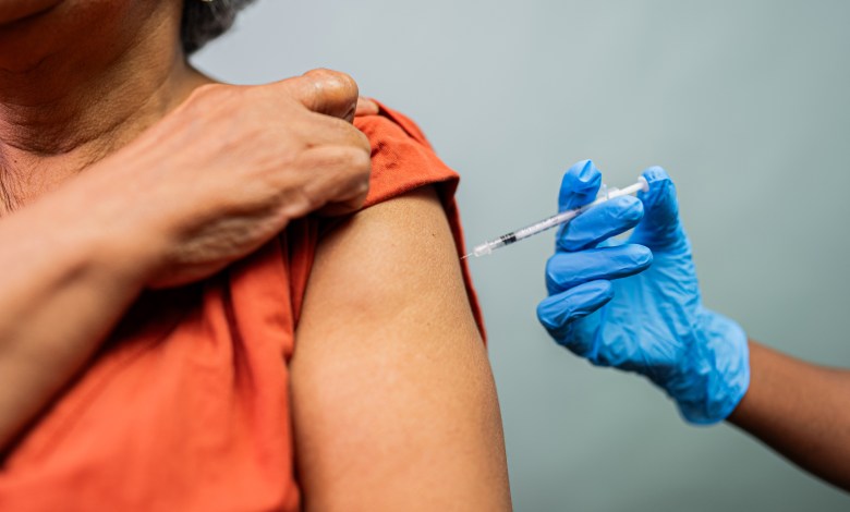 Close-up of a doctor's hand vaccinating a woman in a studio shot