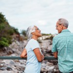 An active and adventurous multiracial senior couple cheerfully chat as they admire the ocean from a scenic coastal overlook near Portland, Maine.