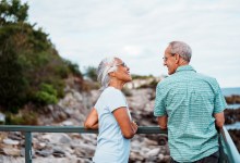 An active and adventurous multiracial senior couple cheerfully chat as they admire the ocean from a scenic coastal overlook near Portland, Maine.