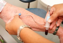 Nurse draws a vial of blood from an elderly woman for a medical test.