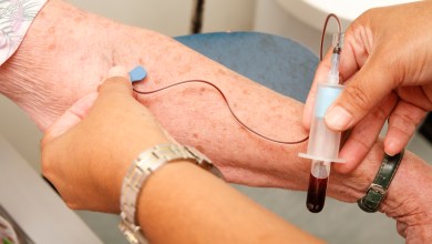 Nurse draws a vial of blood from an elderly woman for a medical test.