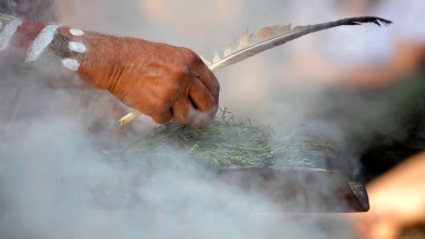 Human hand hold wooden dish and feather at the smoke ritual rite at a indigenous community event in Australia