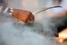 Human hand hold wooden dish and feather at the smoke ritual rite at a indigenous community event in Australia