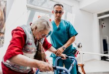Caregiver helping senior woman walk with walker at nursing home