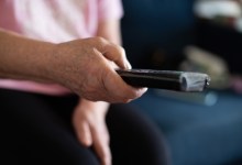 elderly senior woman with remote controller in hands sitting on sofa in living room at home and switching channels watching TV enjoying home leisure in retirement.